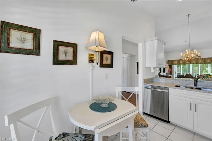Kitchen featuring sink, stainless steel dishwasher, pendant lighting, a chandelier, and white cabinets
