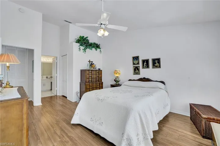 Bedroom with ceiling fan, light wood-type flooring, a high ceiling, and ensuite bath