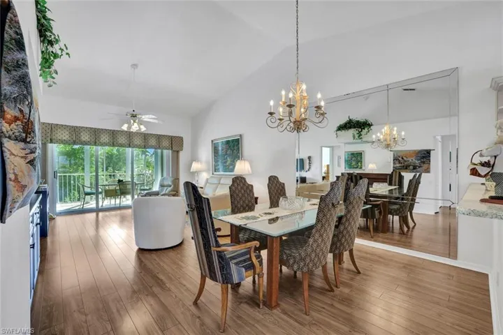 Dining room featuring hardwood / wood-style floors, high vaulted ceiling, and ceiling fan with notable chandelier