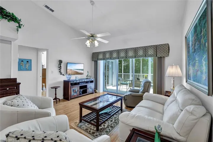 Living room featuring hardwood / wood-style flooring, ceiling fan, and high vaulted ceiling