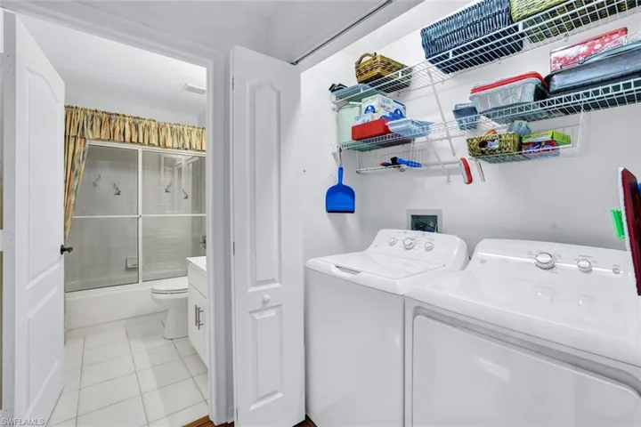 Laundry area featuring light tile patterned floors and washing machine and clothes dryer