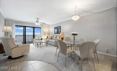 Carpeted dining area with ceiling fan and ornamental molding