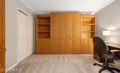 Office with light colored carpet, built in shelves, and crown molding