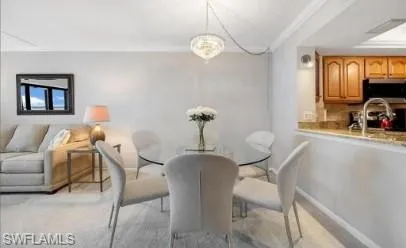 Dining room featuring light colored carpet and ornamental molding