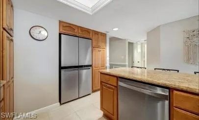 Kitchen featuring stainless steel appliances, light stone counters, wood finish cabinetry, light tile patterned floors, and recessed lighting