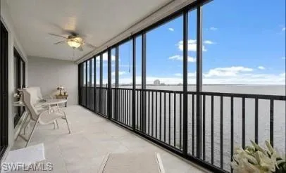 Sunroom / solarium with a balcony, ceiling fan, and a water view
