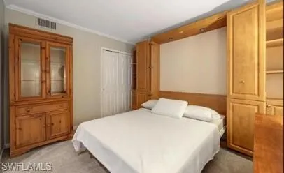 Bedroom featuring light colored carpet, a closet, and crown molding