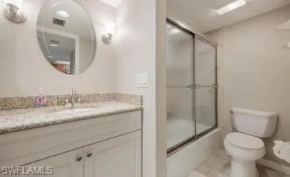 Bathroom with vanity and bath / shower combo with glass door