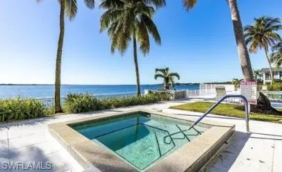 View of swimming pool featuring a swimming pool, a hot tub, a water view, and patio surround