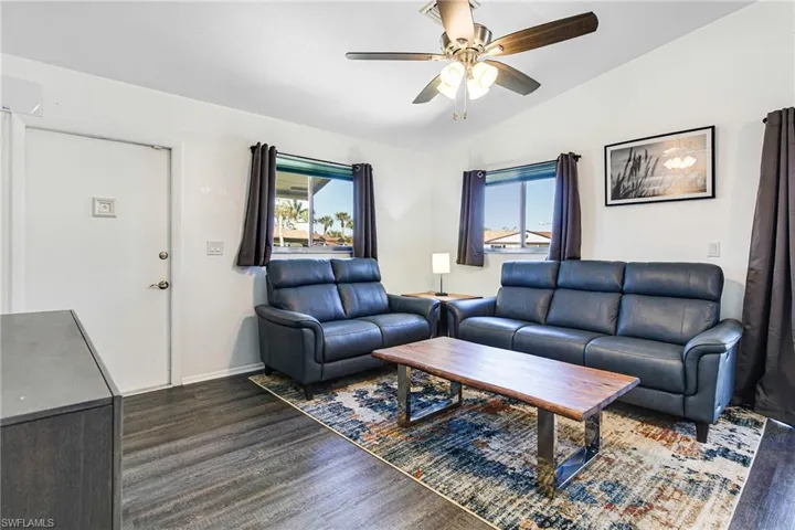 Living area featuring vaulted ceiling, dark wood-style floors, and ceiling fan