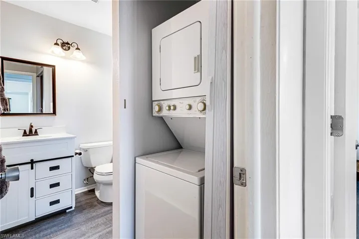 Bathroom featuring vanity, stacked washer and clothes dryer, and dark wood finished floors