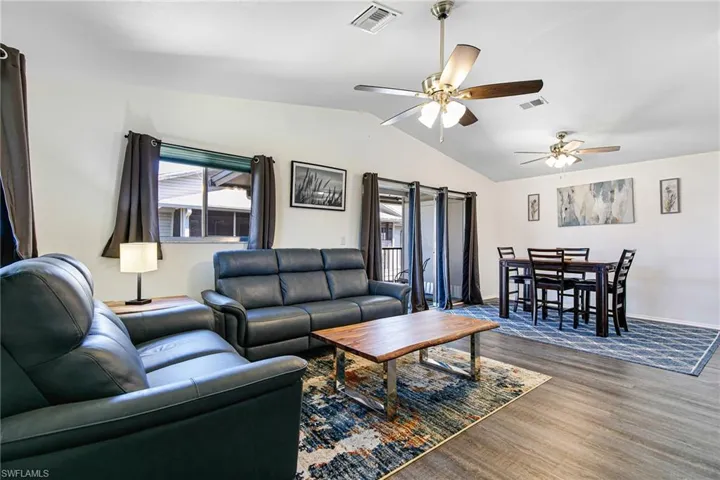 Living room with wood finished floors, vaulted ceiling, and ceiling fan