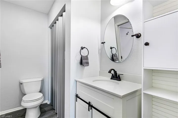 Bathroom with vanity, a shower with shower curtain, and dark wood-style flooring