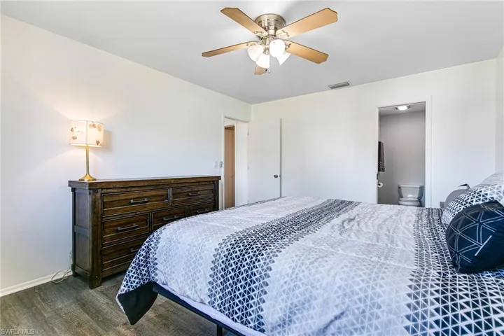 Bedroom featuring ceiling fan, dark wood finished floors, and ensuite bathroom