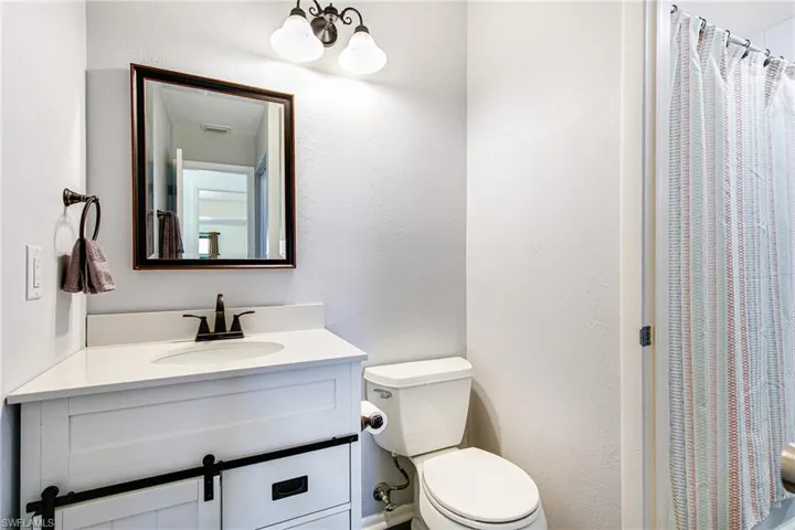 Full bath featuring vanity, a chandelier, curtained shower, and a textured wall