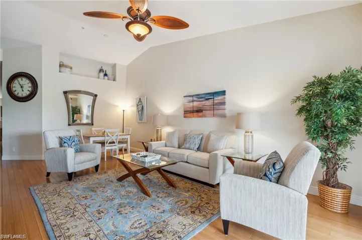 Living room with vaulted ceiling, ceiling fan, and light hardwood / wood-style floors