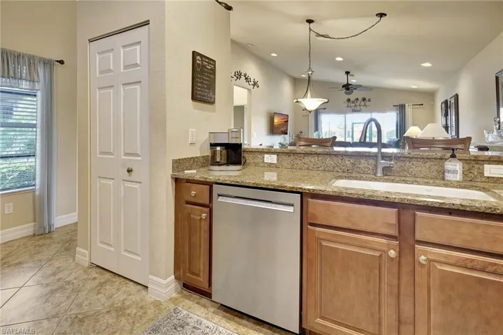 Kitchen with light tile patterned floors, sink, a wealth of natural light, and stainless steel dishwasher