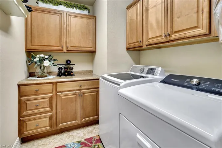 Laundry area with washer and clothes dryer, cabinets, and light tile patterned floors
