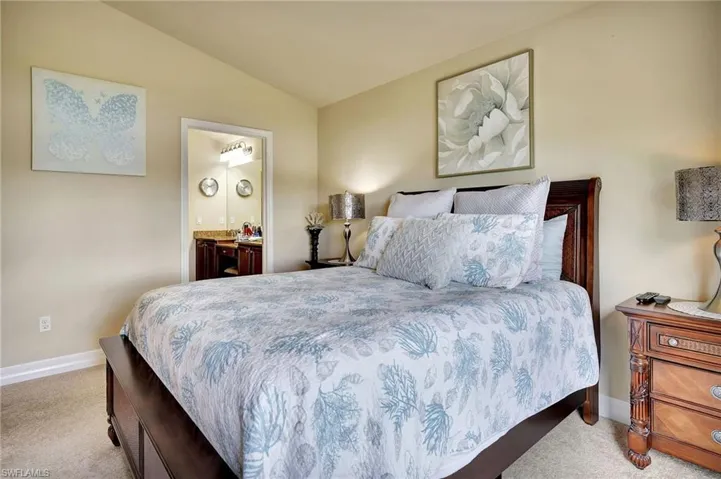 Carpeted bedroom with connected bathroom and lofted ceiling