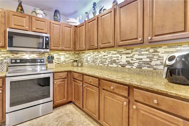 Kitchen with decorative backsplash, electric range oven, and light tile patterned floors