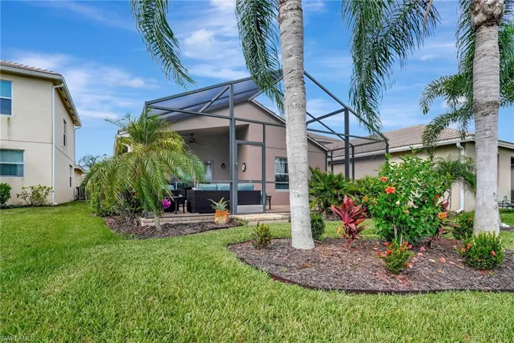 Rear view of property featuring a lanai, a lawn, and ceiling fan