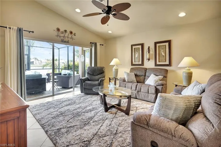 Living room with light tile patterned floors, vaulted ceiling, and ceiling fan