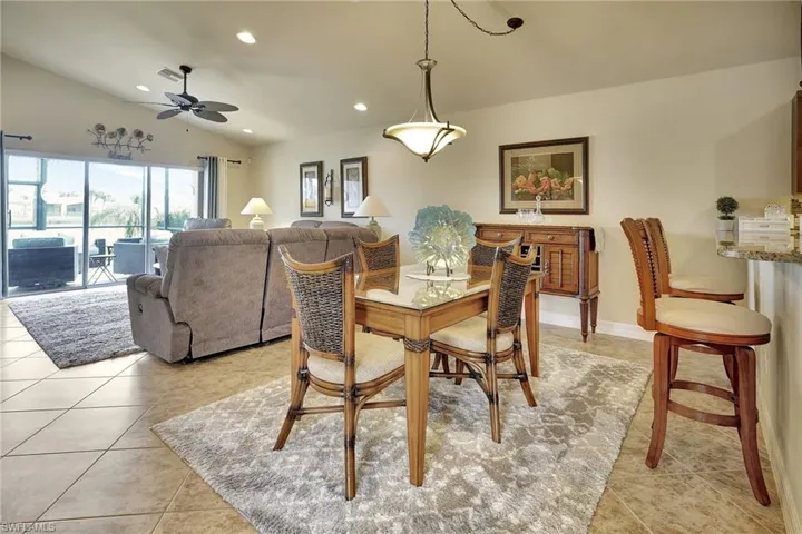 Dining space with lofted ceiling, light tile patterned floors, and ceiling fan