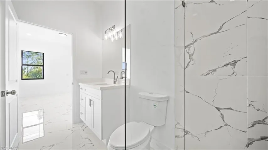 Full bath featuring vanity and light marble finish floors