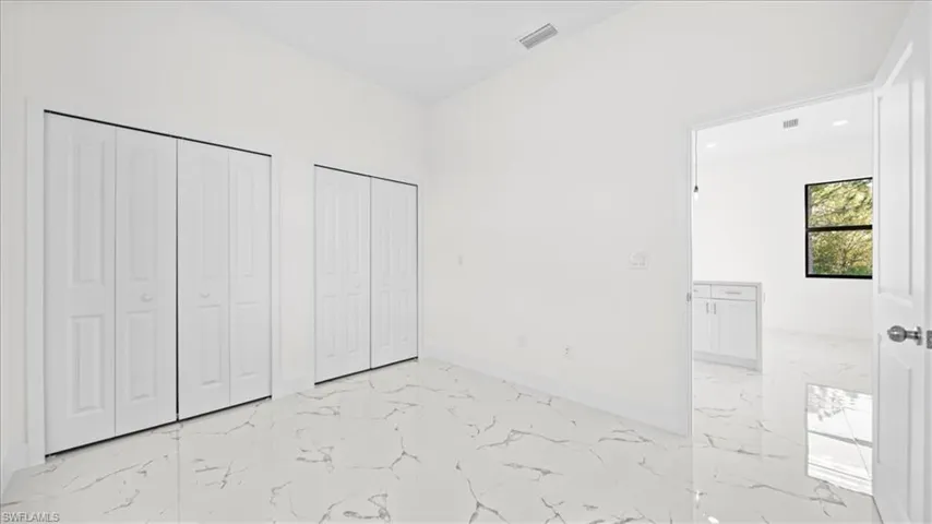 Unfurnished bedroom with multiple closets, light marble finish flooring, and recessed lighting