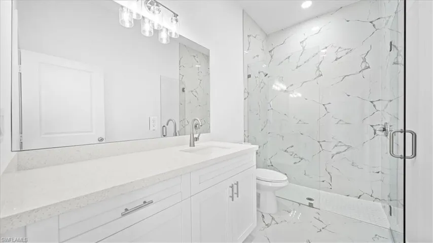 Full bathroom featuring a marble finish shower, vanity, light marble finish flooring, and recessed lighting