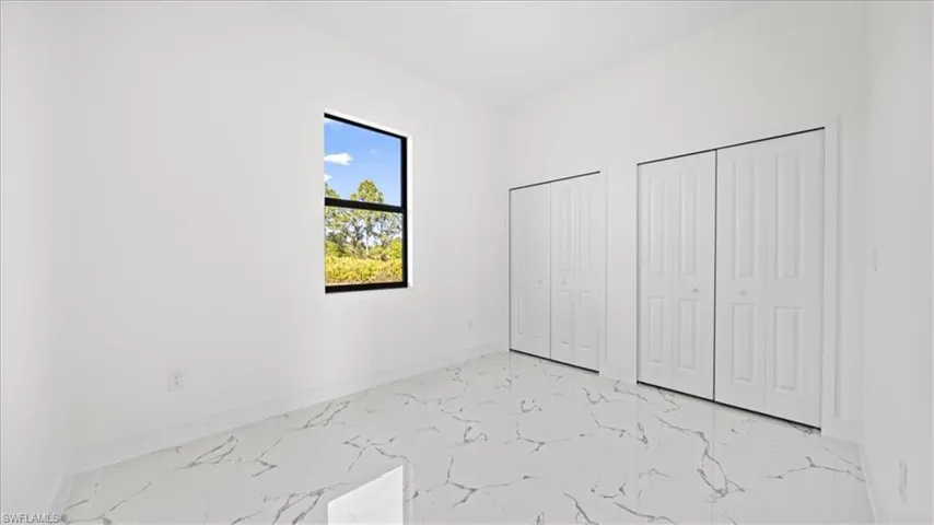 Unfurnished bedroom featuring light marble finish floors and two closets