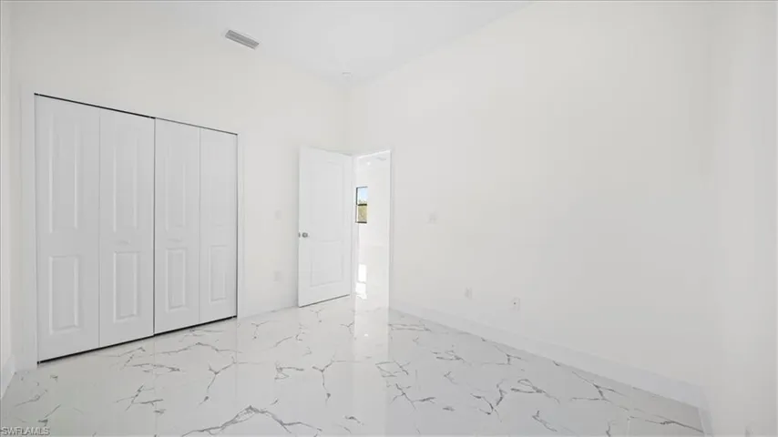Unfurnished bedroom with light marble finish floors and a closet