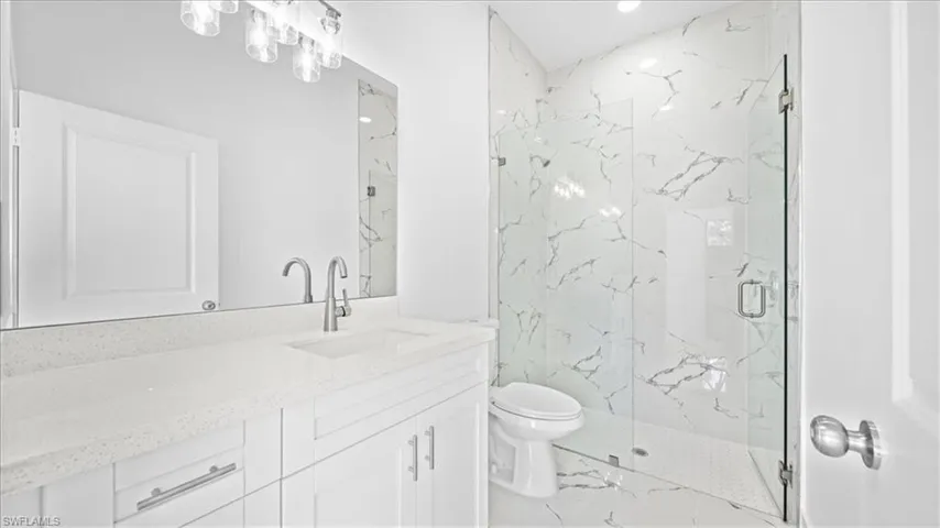 Full bath featuring vanity, a marble finish shower, marble finish floors, and recessed lighting