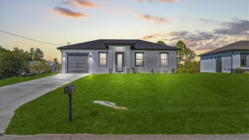 Prairie-style house featuring driveway, a lawn, an attached garage, and stucco siding