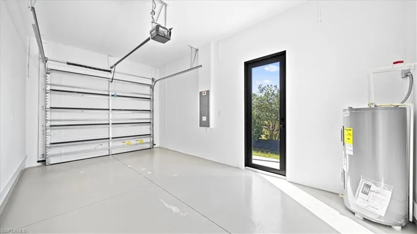 Garage with water heater, electric panel, and a garage door opener