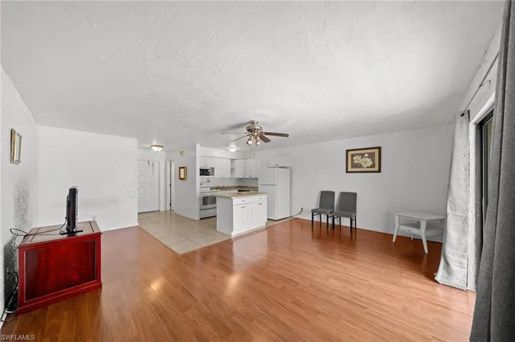 Unfurnished living room featuring light wood-type flooring, a textured ceiling, and ceiling fan