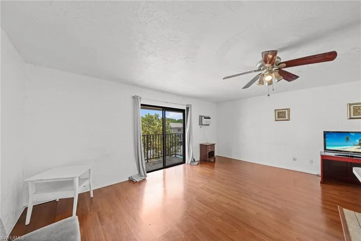 Unfurnished living room featuring light wood-style floors, a textured ceiling, ceiling fan, and a textured wall