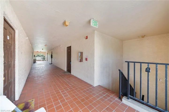 Hall featuring tile patterned floors, a textured wall, and a textured ceiling