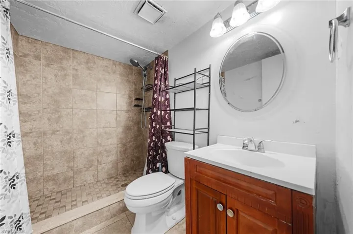 Full bath featuring a stall shower, vanity, a textured ceiling, and tile patterned flooring