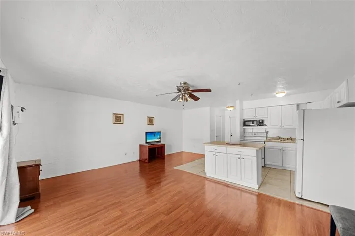 Unfurnished living room featuring light wood-style floors, a textured ceiling, and a ceiling fan