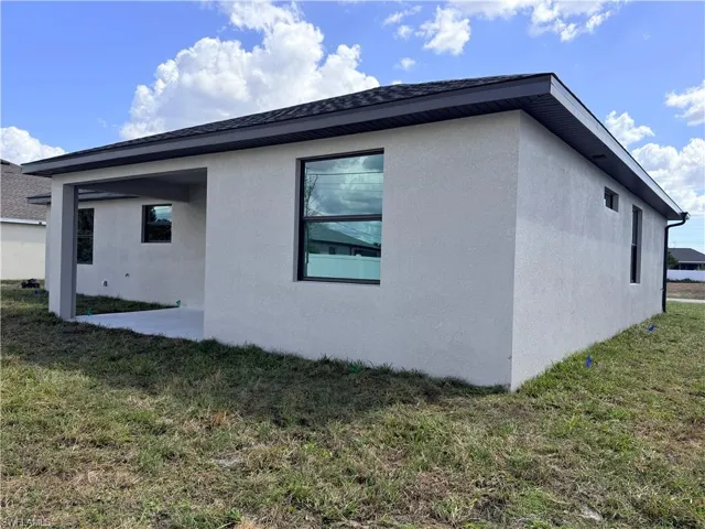 Rear view of house featuring a yard, stucco siding, and a patio