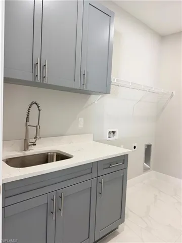 Laundry room featuring electric dryer hookup, hookup for a washing machine, cabinet space, and light marble finish flooring