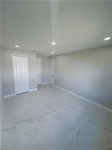 Unfurnished bedroom with recessed lighting, a closet, and light marble finish flooring