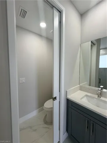 Bathroom featuring vanity, light marble finish flooring, and recessed lighting