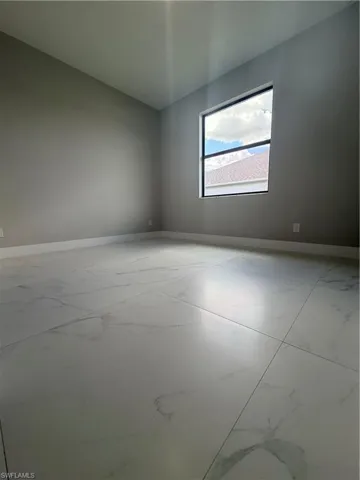 Spare room with light marble finish flooring and baseboards