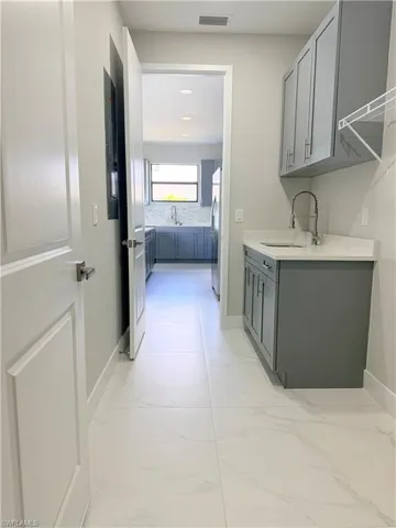 Laundry room featuring light marble finish flooring and a sink