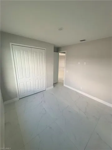 Unfurnished bedroom with light marble finish flooring and a closet