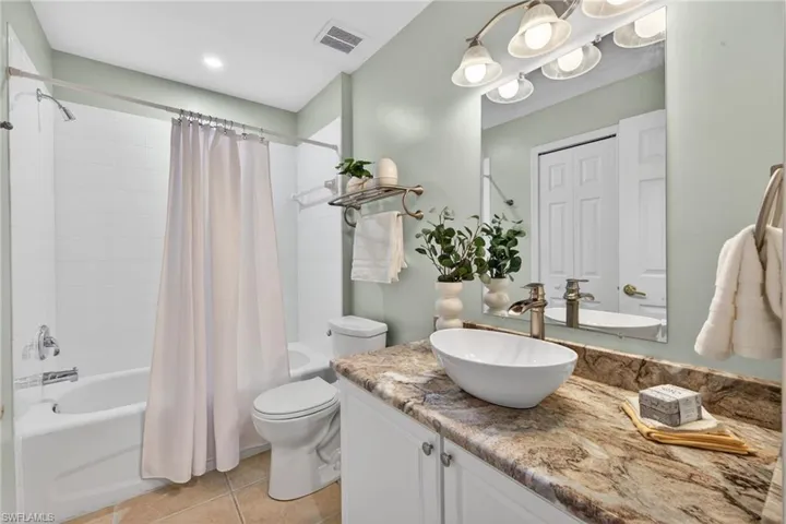 Bathroom with vanity, shower / tub combo with curtain, and light tile patterned floors