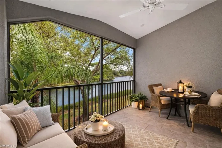 Sunroom / solarium with vaulted ceiling, ceiling fan, a balcony, and a water view