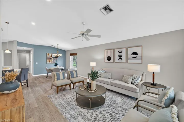 Living area with light wood-style floors, lofted ceiling, ceiling fan, and hanging lights